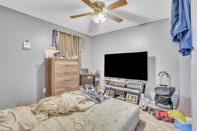 tiled bedroom with ceiling fan, baseboards, and a textured ceiling