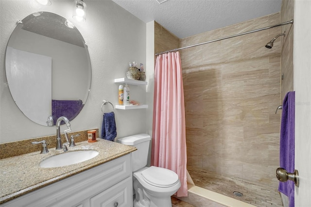 bathroom featuring vanity, toilet, a stall shower, and a textured ceiling