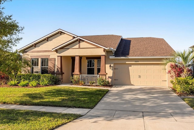 craftsman-style home with a front lawn, a porch, concrete driveway, stucco siding, and an attached garage