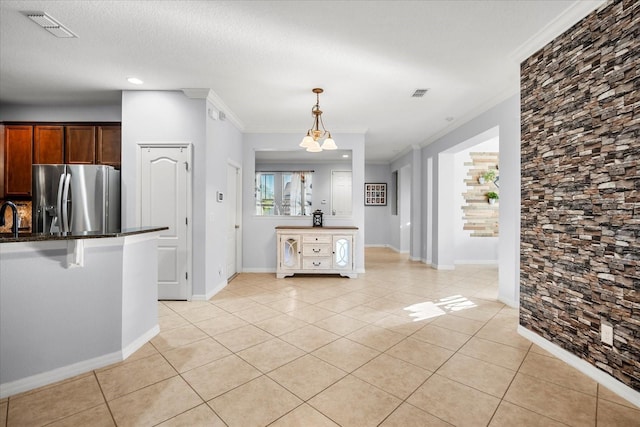 kitchen with visible vents, stainless steel fridge, light tile patterned flooring, and crown molding