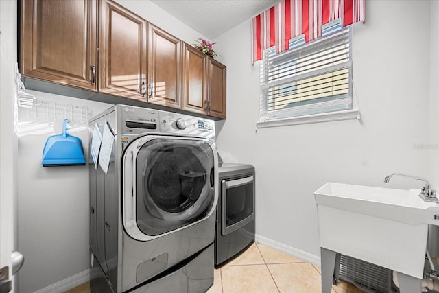 washroom with baseboards, light tile patterned floors, separate washer and dryer, cabinet space, and a sink