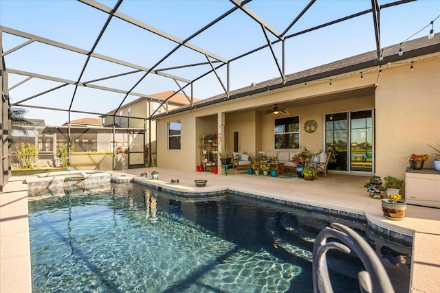 view of pool with glass enclosure, a pool with connected hot tub, a ceiling fan, and a patio