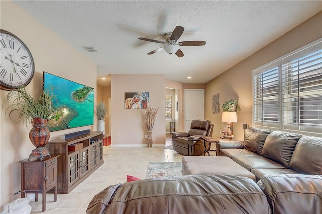 living area with visible vents, a textured ceiling, light tile patterned flooring, baseboards, and ceiling fan