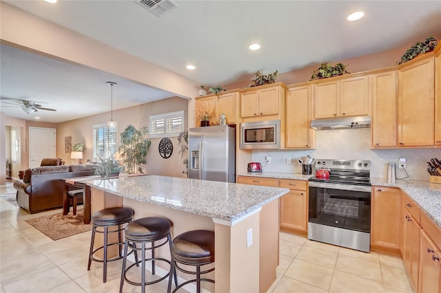 kitchen with visible vents, light brown cabinetry, under cabinet range hood, a center island, and stainless steel appliances