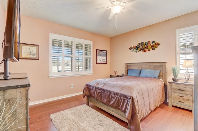 bedroom featuring ceiling fan, baseboards, a textured ceiling, and wood finished floors