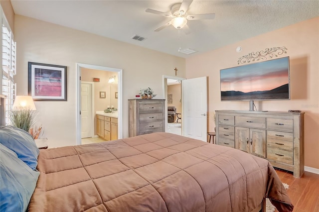 bedroom with visible vents, light wood-style flooring, ensuite bathroom, baseboards, and ceiling fan