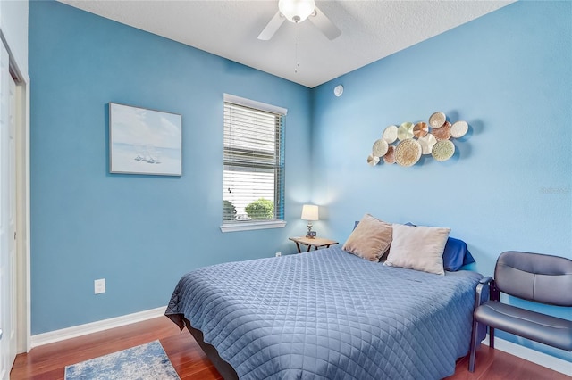 bedroom featuring ceiling fan, baseboards, and wood finished floors