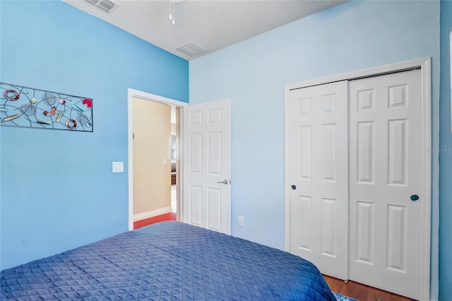 unfurnished bedroom with visible vents, a textured ceiling, a closet, and wood finished floors