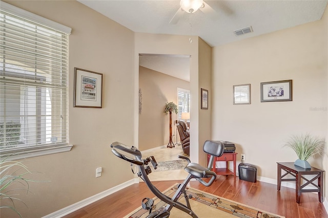 workout area featuring ceiling fan, visible vents, baseboards, and wood finished floors