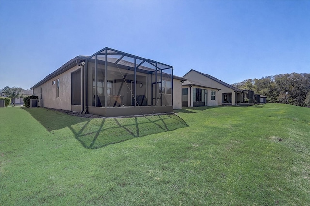 rear view of house with glass enclosure, central AC, and a yard