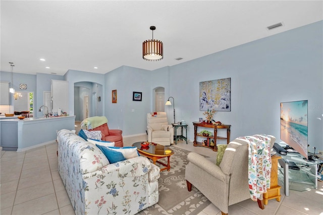 living area with light tile patterned floors, visible vents, arched walkways, and recessed lighting