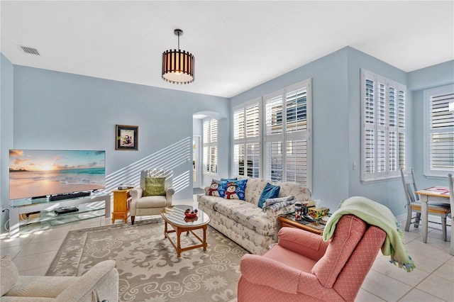 living area featuring arched walkways, visible vents, tile patterned flooring, and baseboards