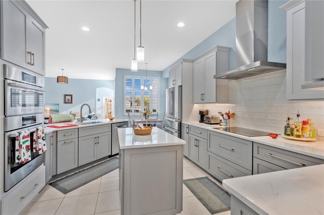 kitchen featuring gray cabinetry, a sink, stainless steel appliances, wall chimney range hood, and decorative backsplash