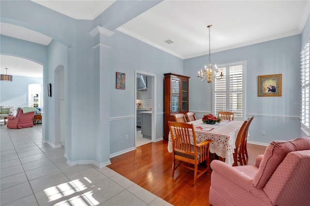 dining area featuring a notable chandelier, visible vents, arched walkways, and crown molding