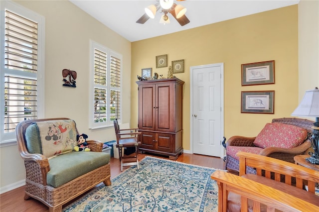 living area featuring baseboards, wood finished floors, and a ceiling fan