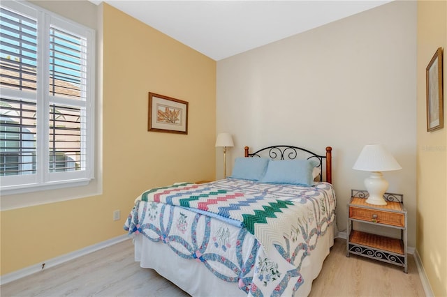 bedroom with baseboards, multiple windows, and wood finished floors