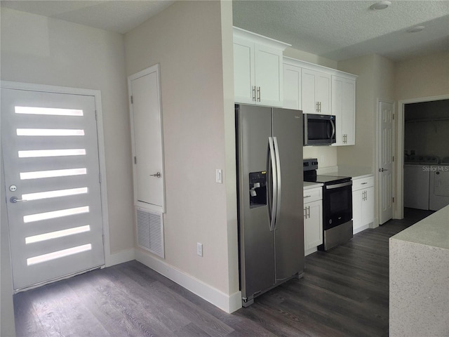 kitchen featuring appliances with stainless steel finishes, washing machine and dryer, dark wood-style flooring, and white cabinets