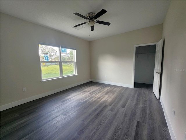 unfurnished bedroom with dark wood-style floors, baseboards, a closet, and ceiling fan