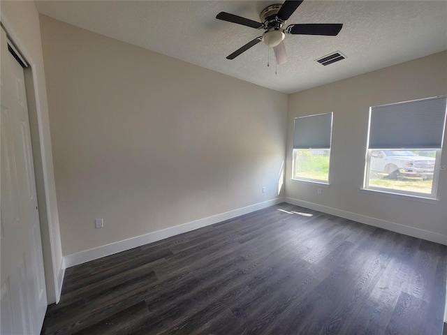 spare room with dark wood-type flooring, baseboards, visible vents, and a textured ceiling