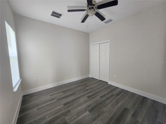 unfurnished bedroom with dark wood-style floors, visible vents, and baseboards