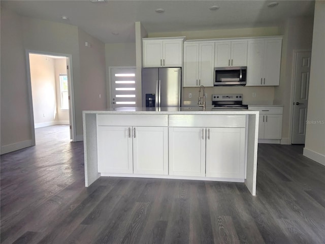 kitchen with stainless steel appliances, dark wood-type flooring, a kitchen island with sink, and white cabinetry