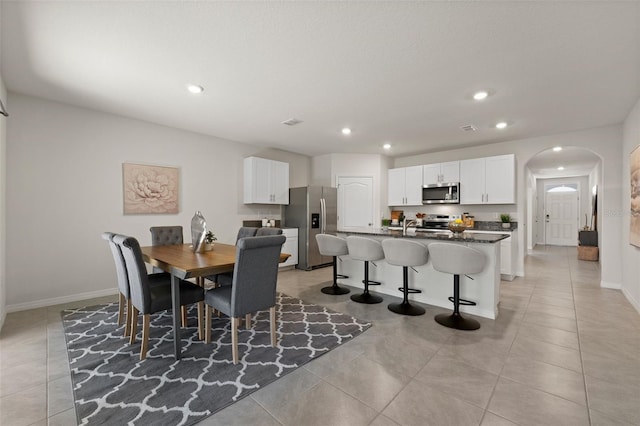 dining space featuring visible vents, baseboards, light tile patterned flooring, recessed lighting, and arched walkways