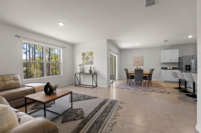 living room featuring visible vents, baseboards, light tile patterned flooring, recessed lighting, and a textured ceiling