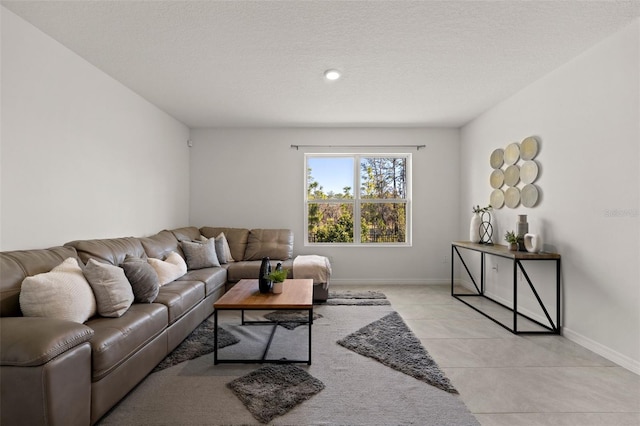 living area with light tile patterned floors, baseboards, and a textured ceiling