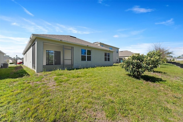 back of house with stucco siding and a yard