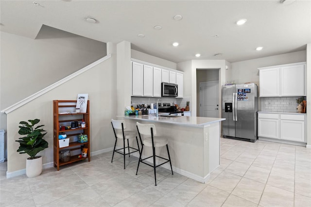 kitchen featuring a breakfast bar, a peninsula, white cabinets, and appliances with stainless steel finishes