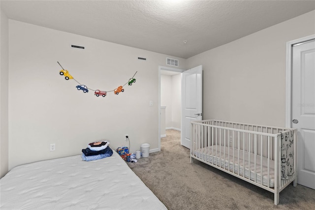 bedroom with visible vents, baseboards, a textured ceiling, and carpet flooring