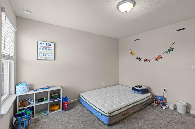 carpeted bedroom with visible vents, a textured ceiling, and baseboards