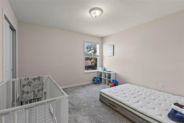 bedroom with carpet, baseboards, a closet, and a textured ceiling