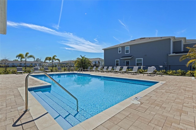 community pool with a patio and fence