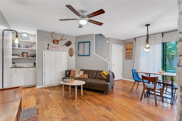 living room with baseboards, light wood-type flooring, and ceiling fan