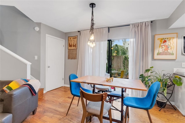 dining space with stairs, light wood-style flooring, and baseboards