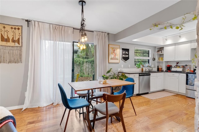 dining space featuring light wood-type flooring, baseboards, an inviting chandelier, and track lighting