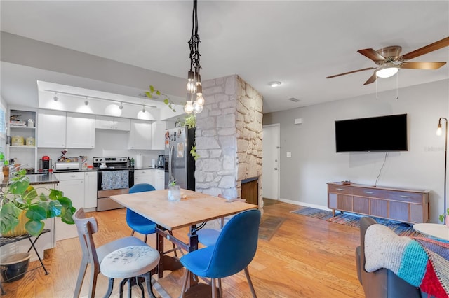 dining room with a fireplace, baseboards, light wood-type flooring, and a ceiling fan