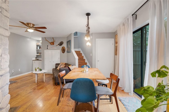 dining space featuring light wood-style flooring, baseboards, stairs, and ceiling fan