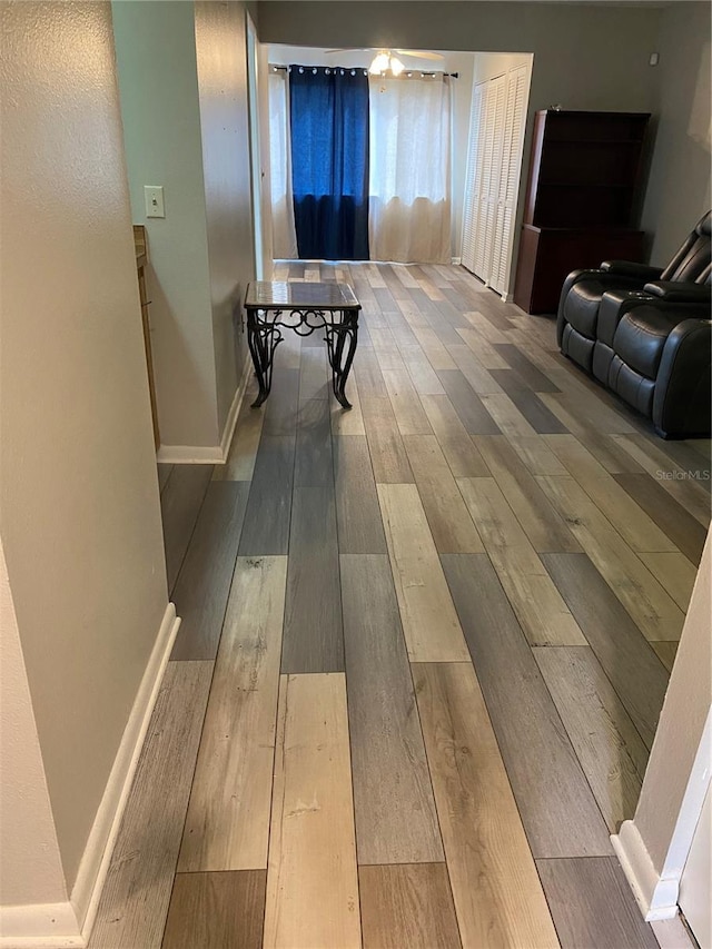 hall with baseboards and wood finished floors