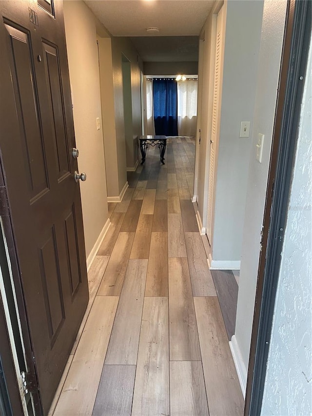 hall with light wood-type flooring and baseboards