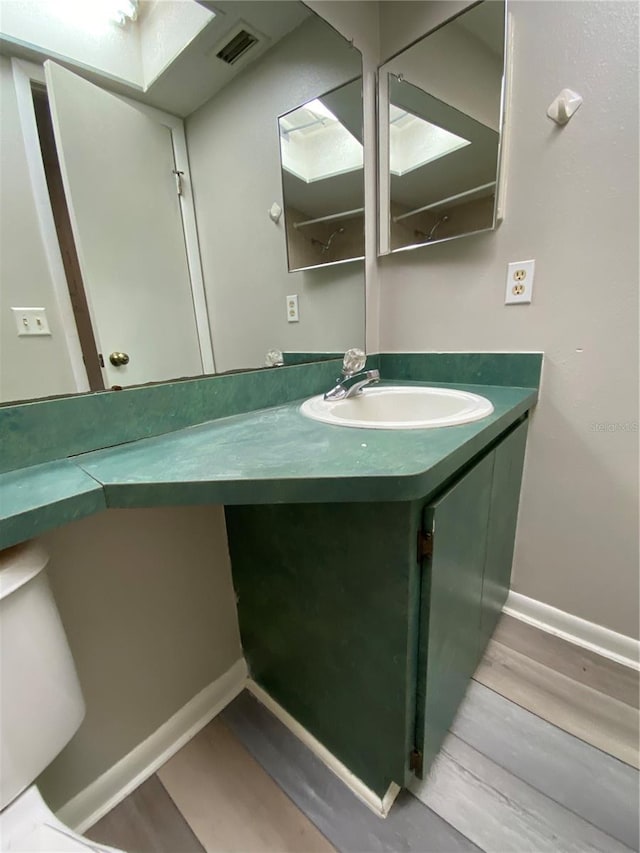 bathroom featuring visible vents, vanity, baseboards, and wood finished floors