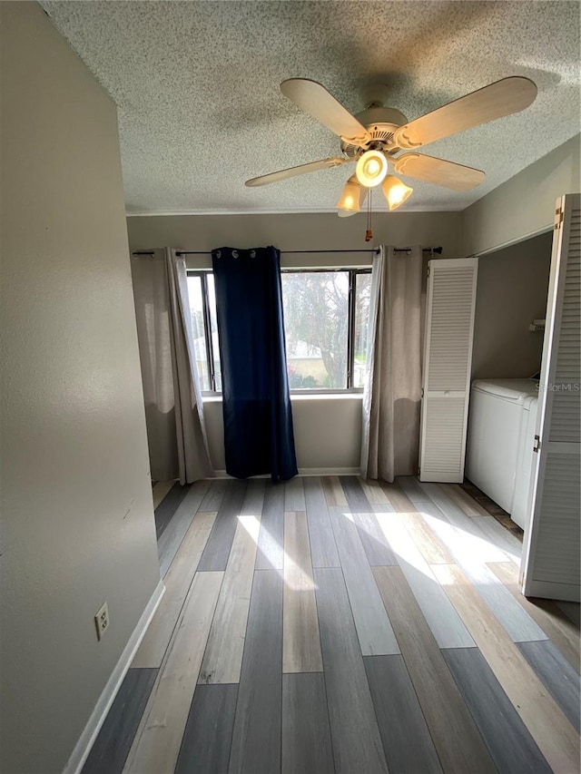 unfurnished bedroom with a textured ceiling, a ceiling fan, baseboards, and wood finished floors