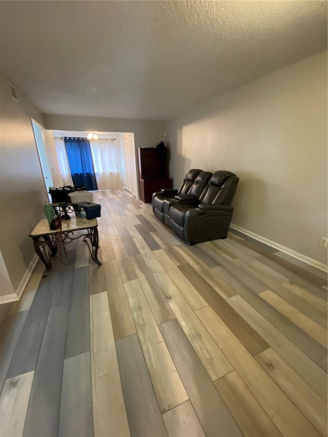 living room featuring wood finished floors, baseboards, and a textured ceiling