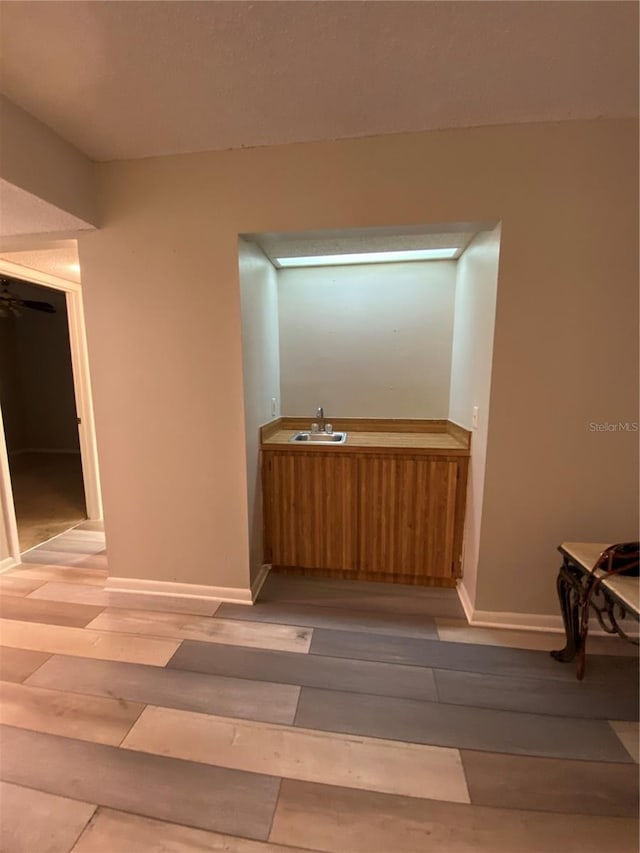 corridor with a sink, baseboards, and light wood finished floors