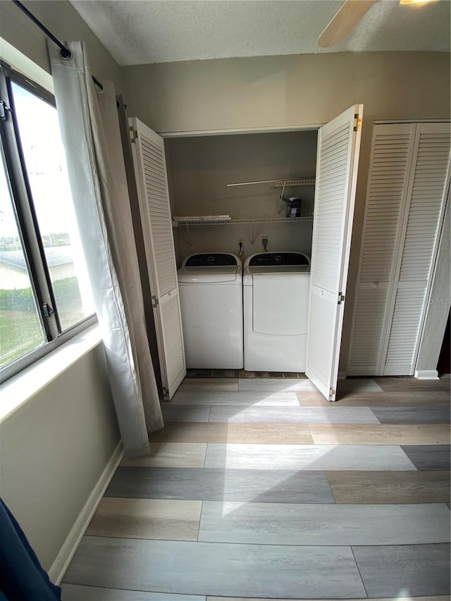 washroom with baseboards, wood tiled floor, washing machine and dryer, laundry area, and a textured ceiling