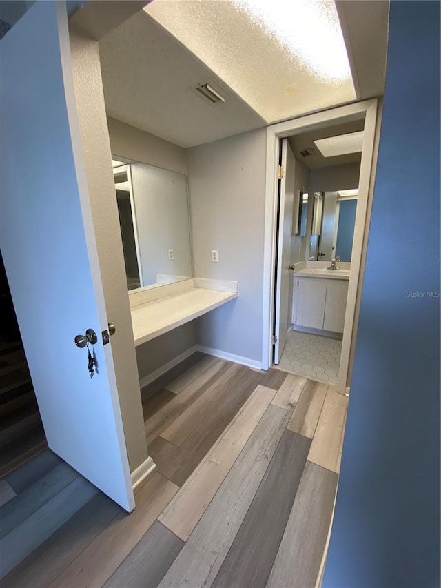 bathroom featuring a textured ceiling, vanity, baseboards, and wood finished floors