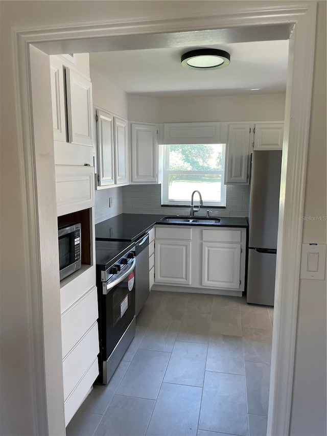 kitchen with dark countertops, appliances with stainless steel finishes, white cabinetry, and a sink