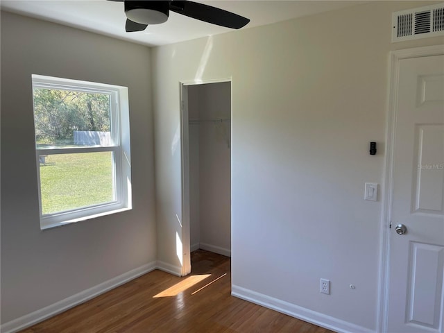 unfurnished bedroom featuring a closet, visible vents, baseboards, and wood finished floors