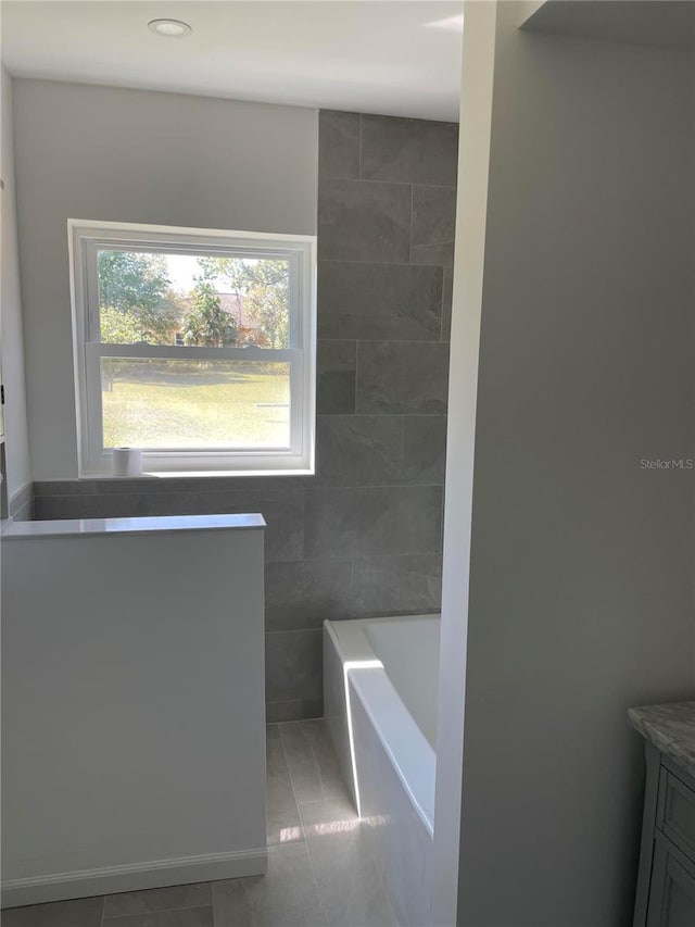 bathroom with vanity, tile walls, a bathtub, and tile patterned flooring